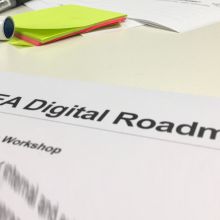 Image of area of tabletop with markers and sticky notes and part of a page titled "WGEA Digital Roadmap"